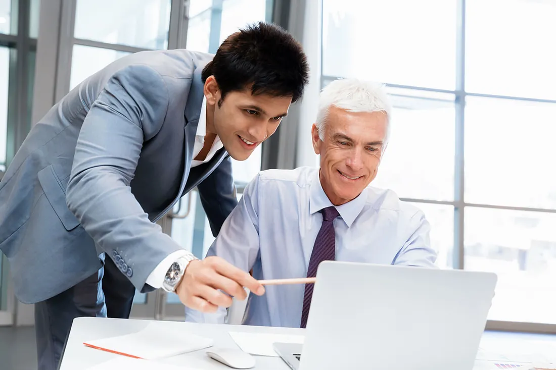 Two colleagues reviewing a candidate profile together on a laptop